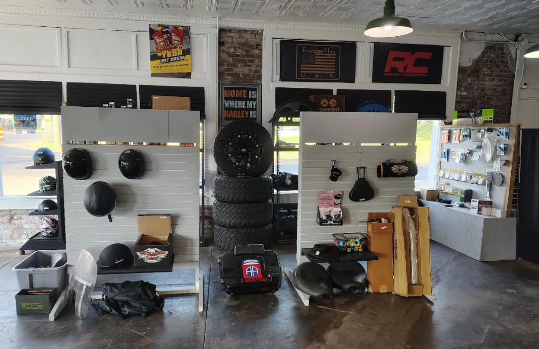 Motorcycle parts and accessories displayed in a shop, including helmets, tires, and exhaust systems.