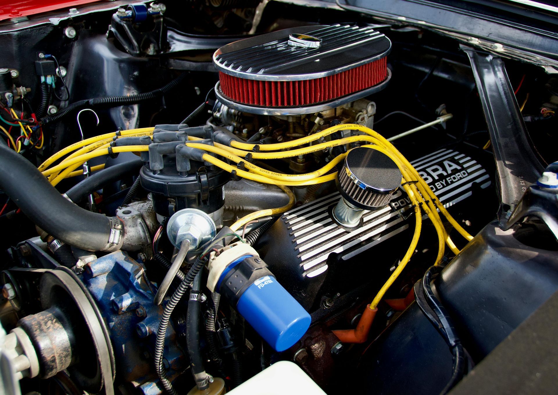 Ford Cobra engine, black and silver, with yellow wires and red air filter.