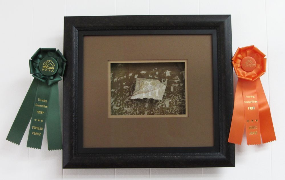 A camera is sitting on a wooden table next to a laptop and a cell phone.