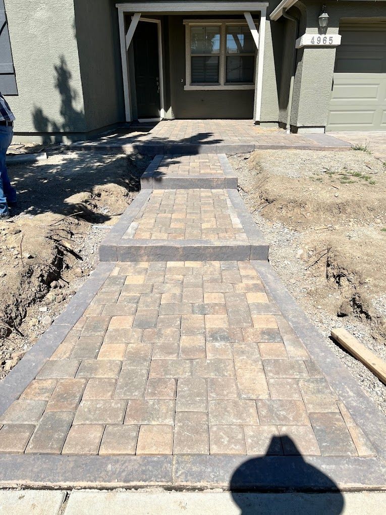 A brick walkway is being built in front of a house.