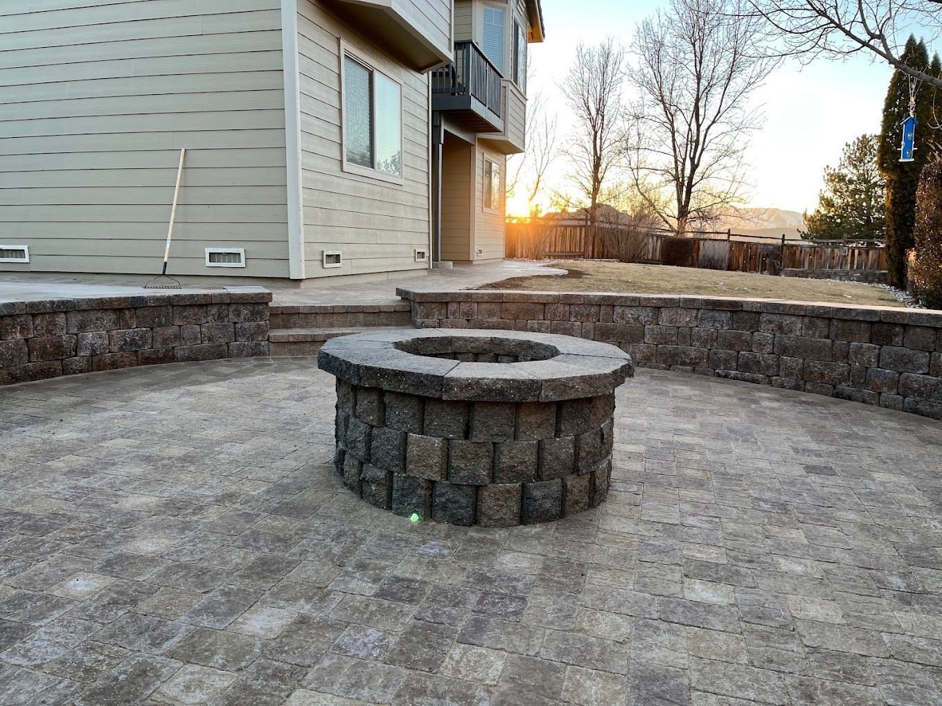 A fire pit is sitting on a patio in front of a house.