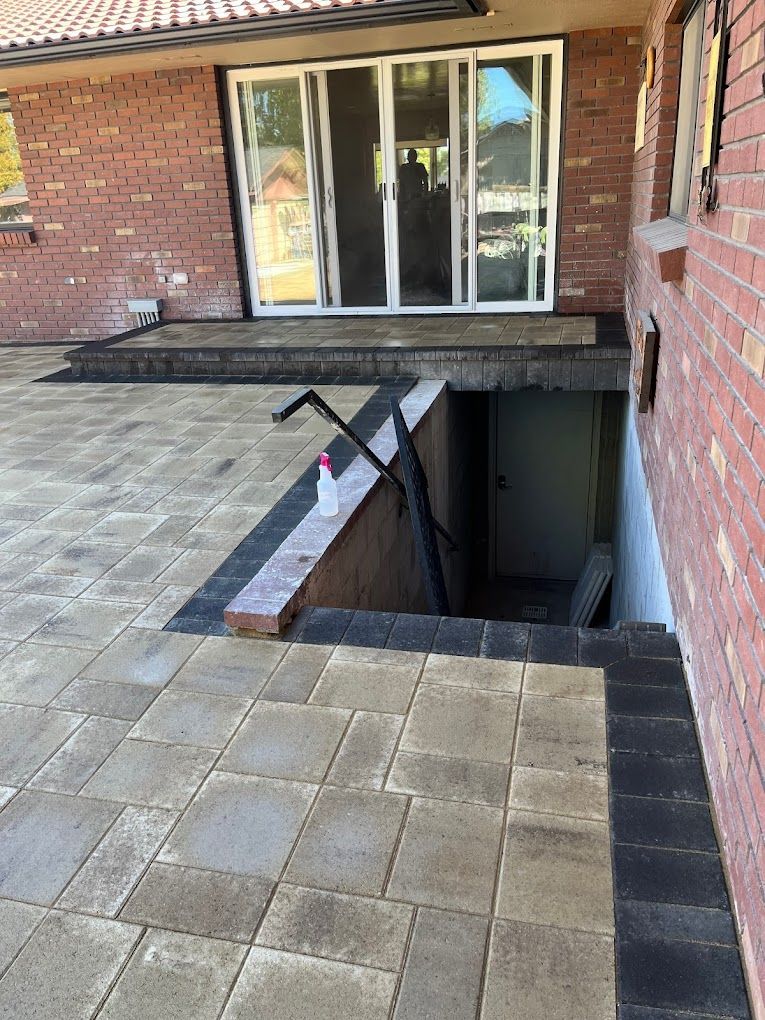 A brick house with a patio and stairs leading to a basement.
