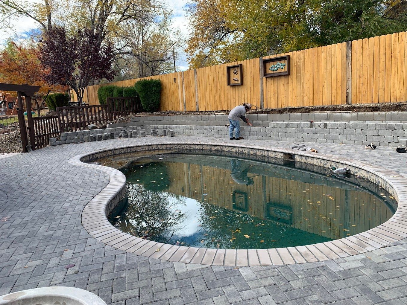 A man is working on a swimming pool in a backyard.