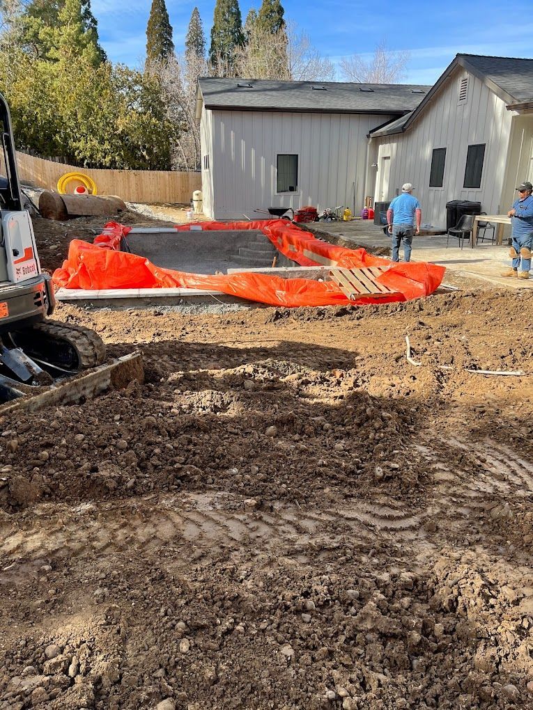 A construction site with a house in the background and a bulldozer in the foreground.
