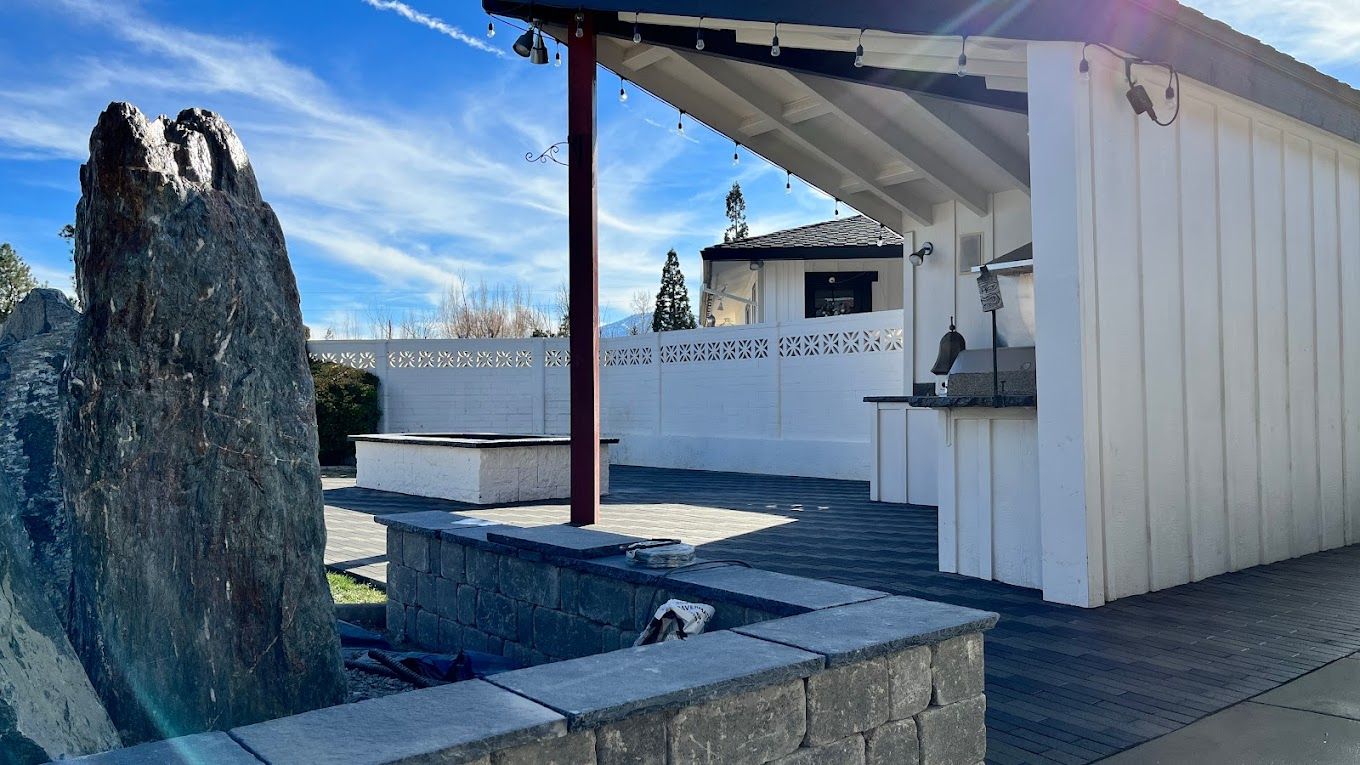 A white building with a large rock in front of it.