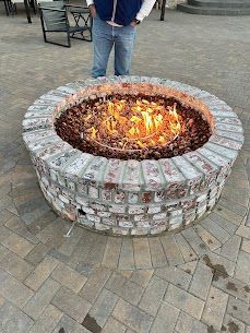 A man is standing next to a fire pit on a patio.