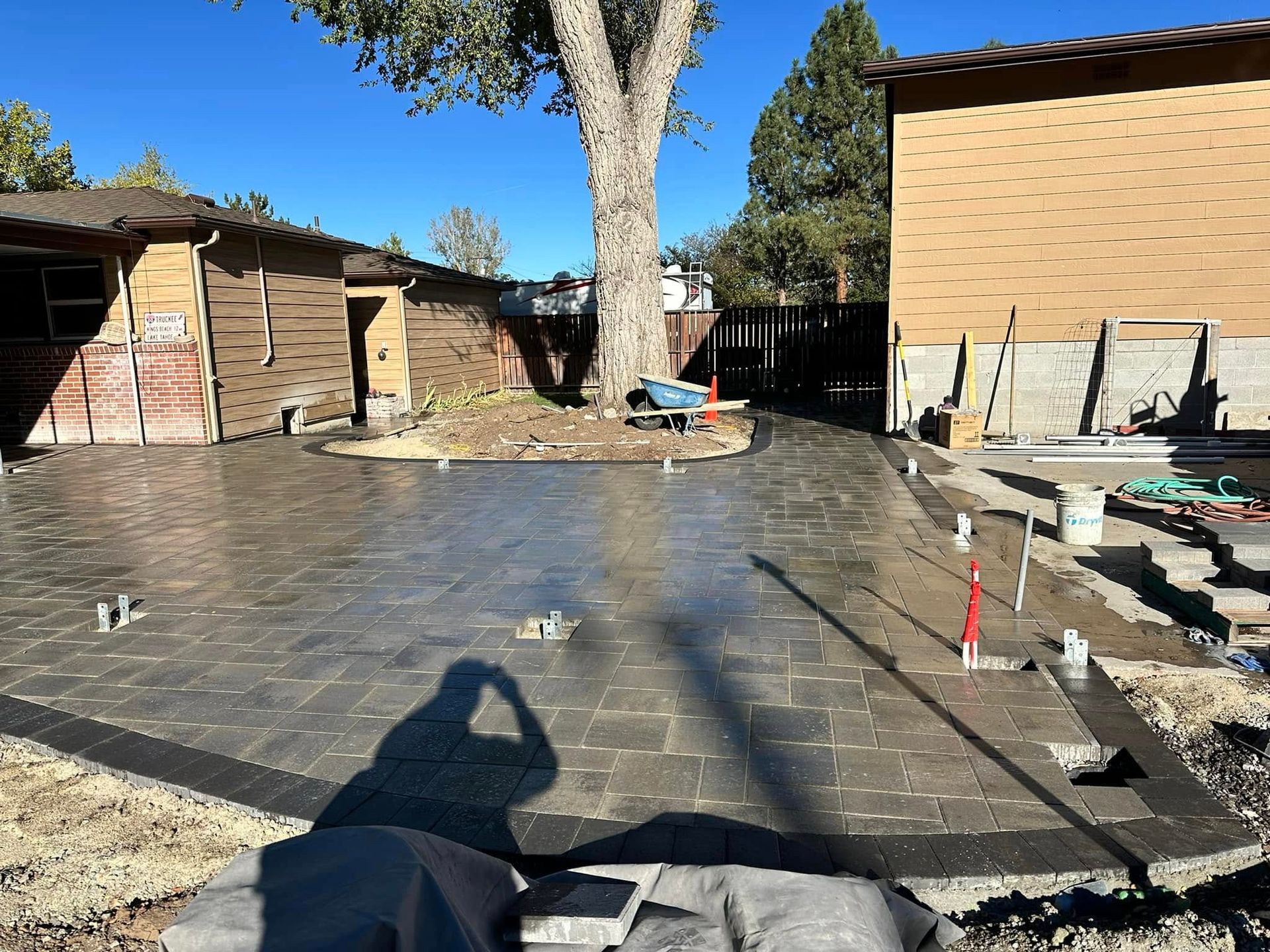 A person is taking a picture of a concrete driveway in front of a house.