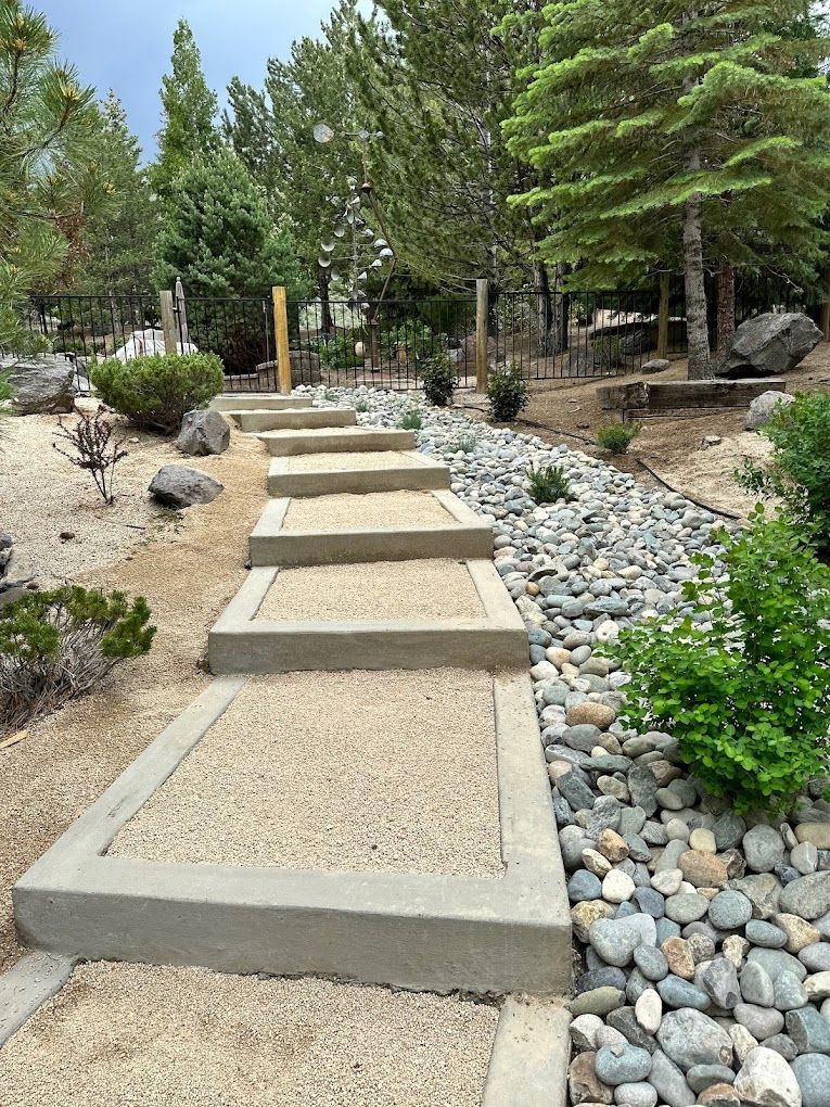 A row of concrete steps leading up to a rocky path in a park.