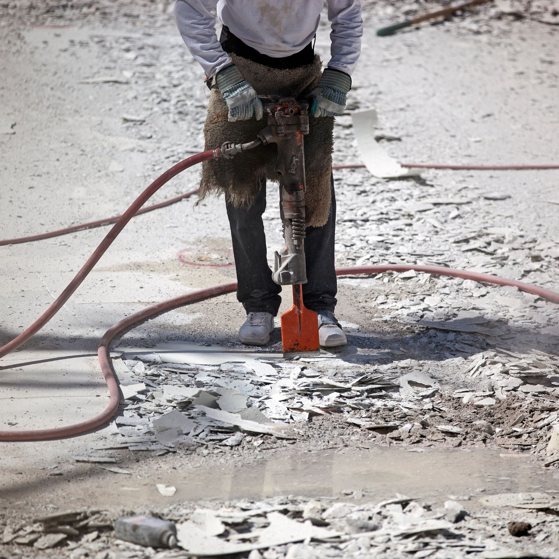 A man is using a hammer to break up concrete