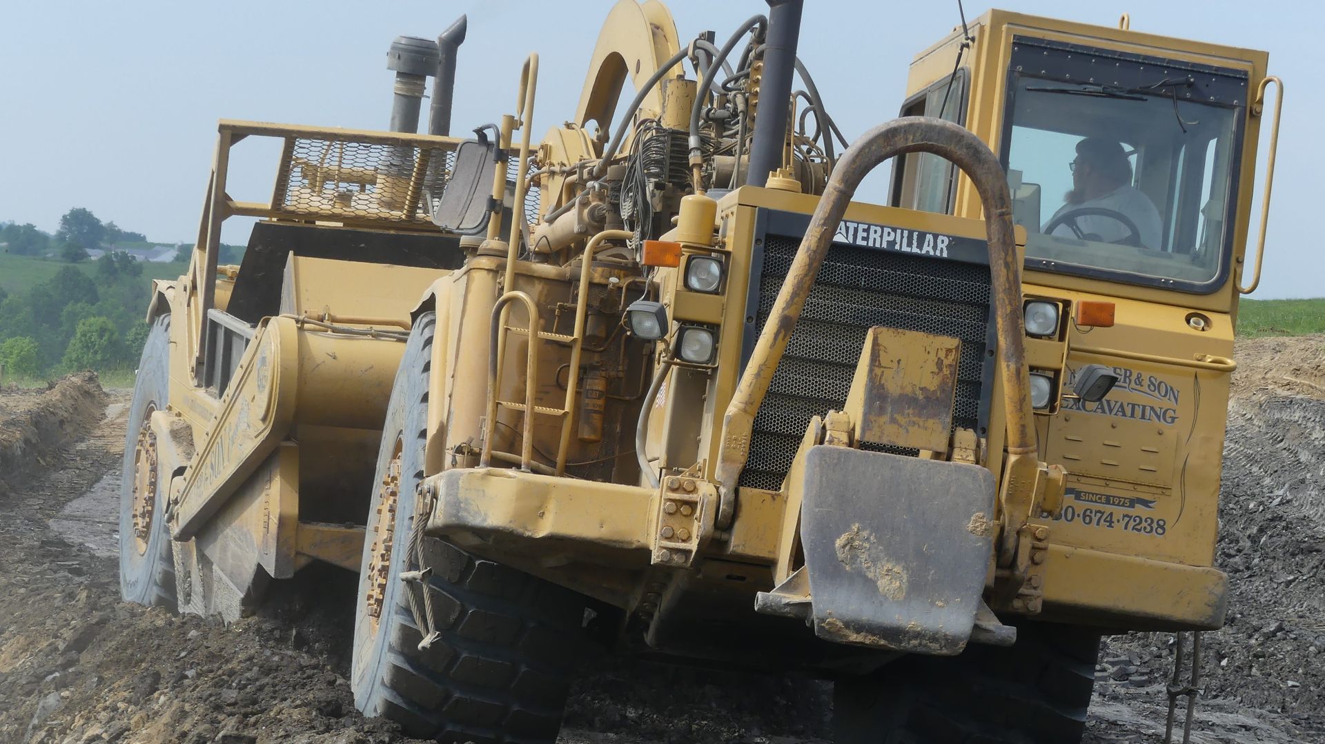 Yellow earthmover moving dirt on construction site.