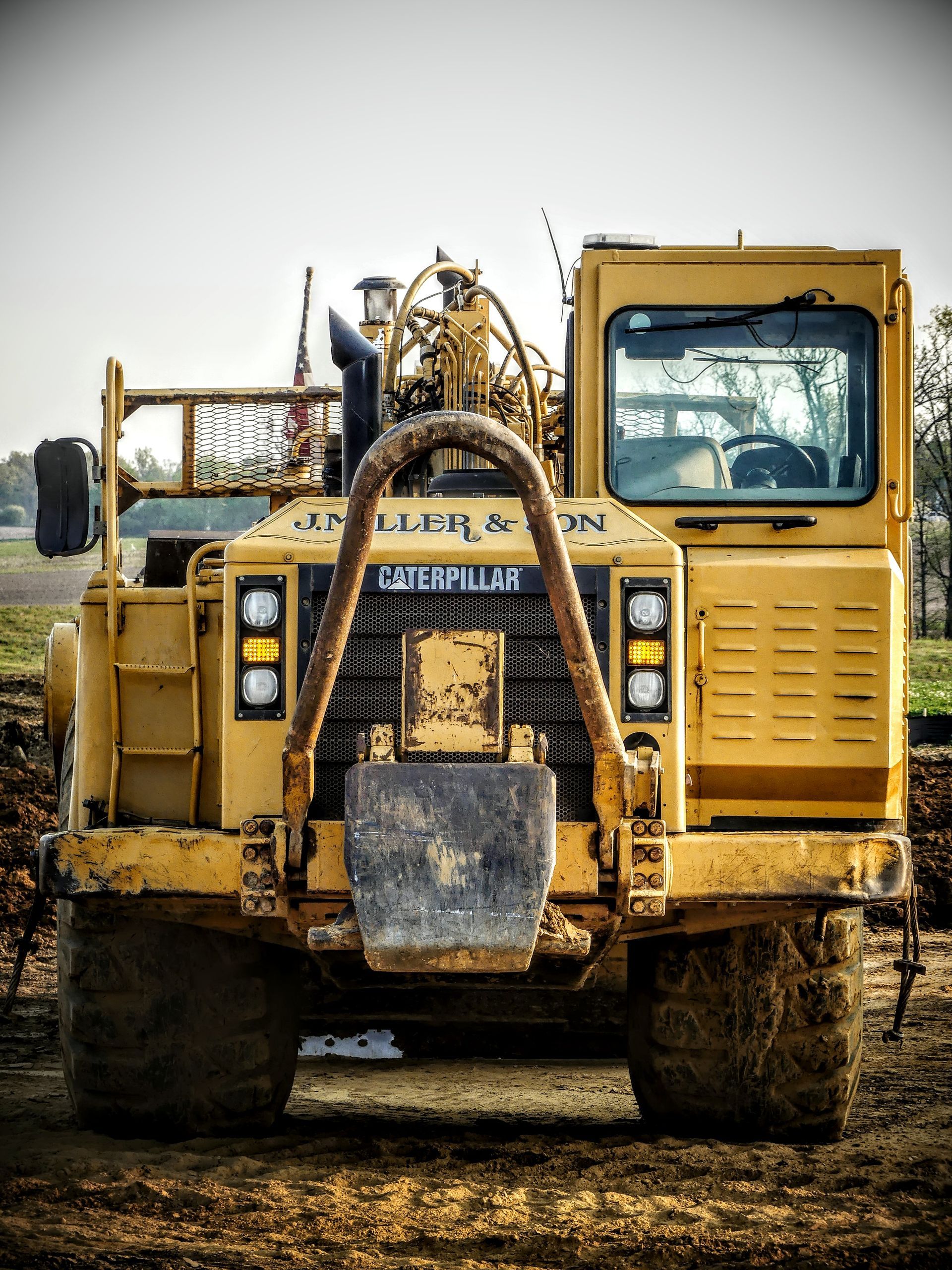Yellow Caterpillar compactor on a construction site, front view.