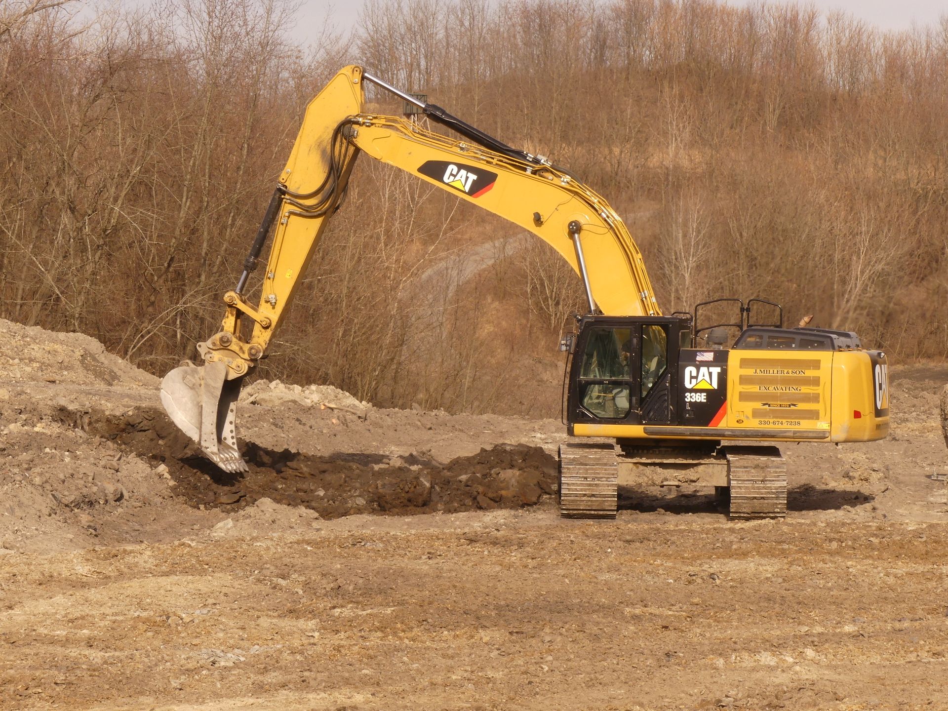 Yellow CAT excavator digging in dirt on a construction site.