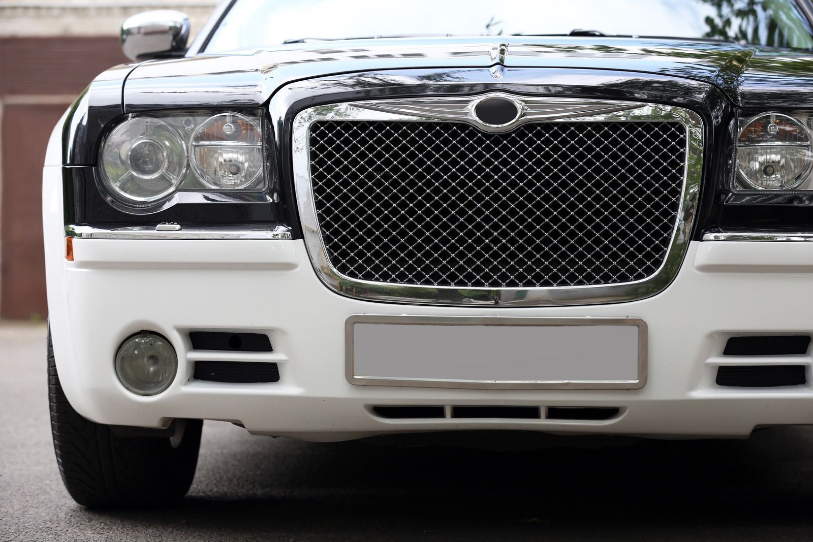 Close-up front view of a two-tone black and white Chrysler 300 luxury sedan with a chrome mesh grille.