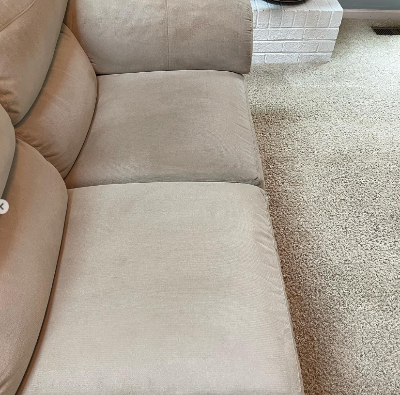 a beige couch is sitting on a carpeted floor in a living room .