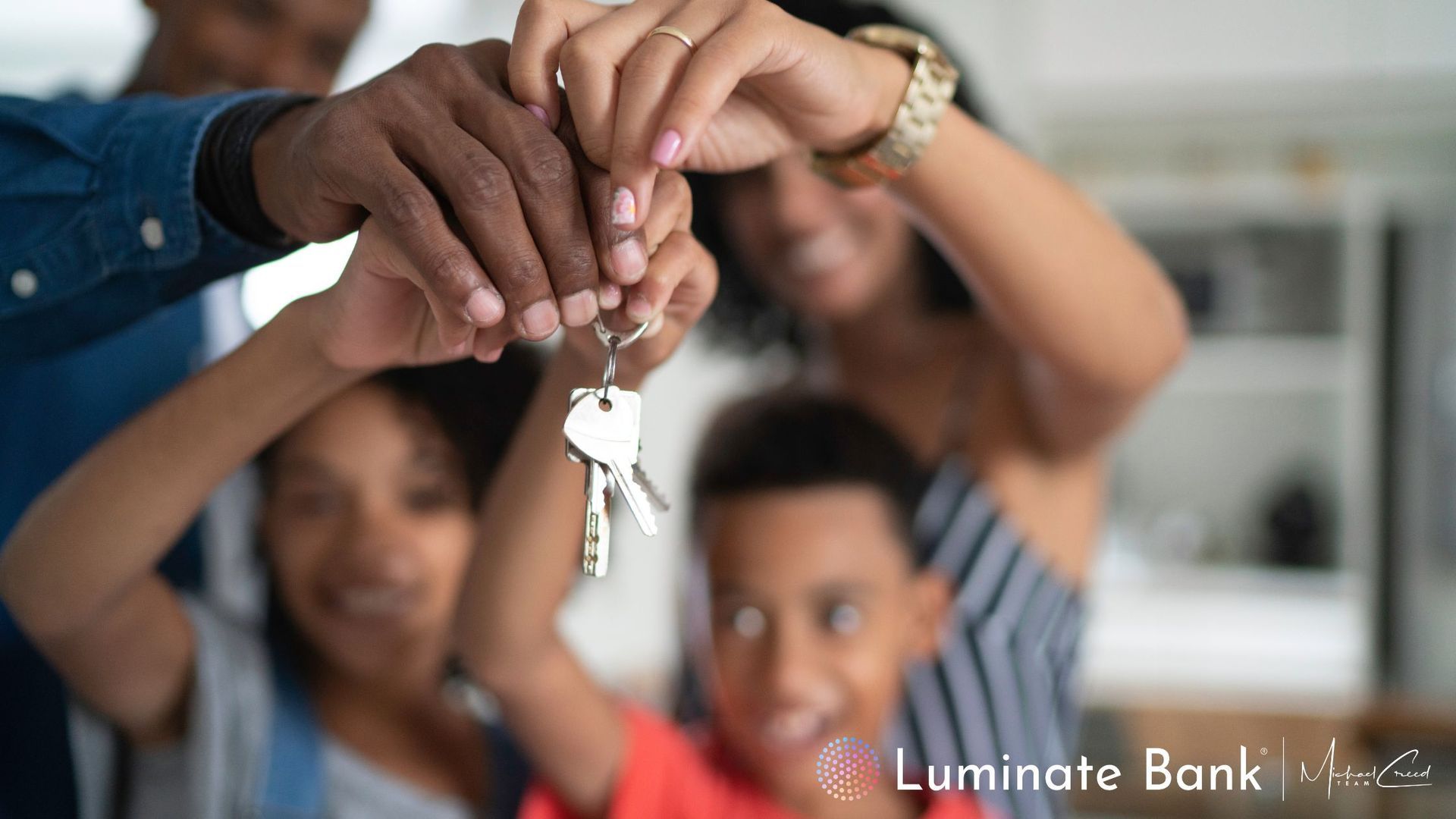 Family holding new keys to their home; they are all looking at the keys. 