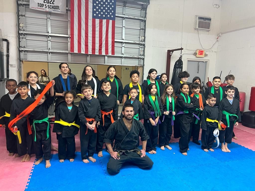 A group of children in karate uniforms are posing for a picture in a gym.