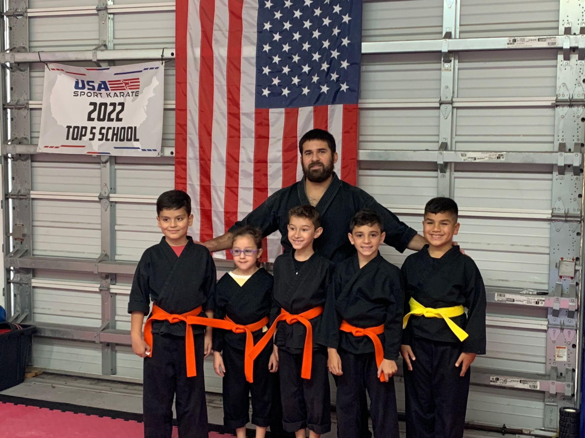 A group of young boys are posing for a picture in front of an american flag.