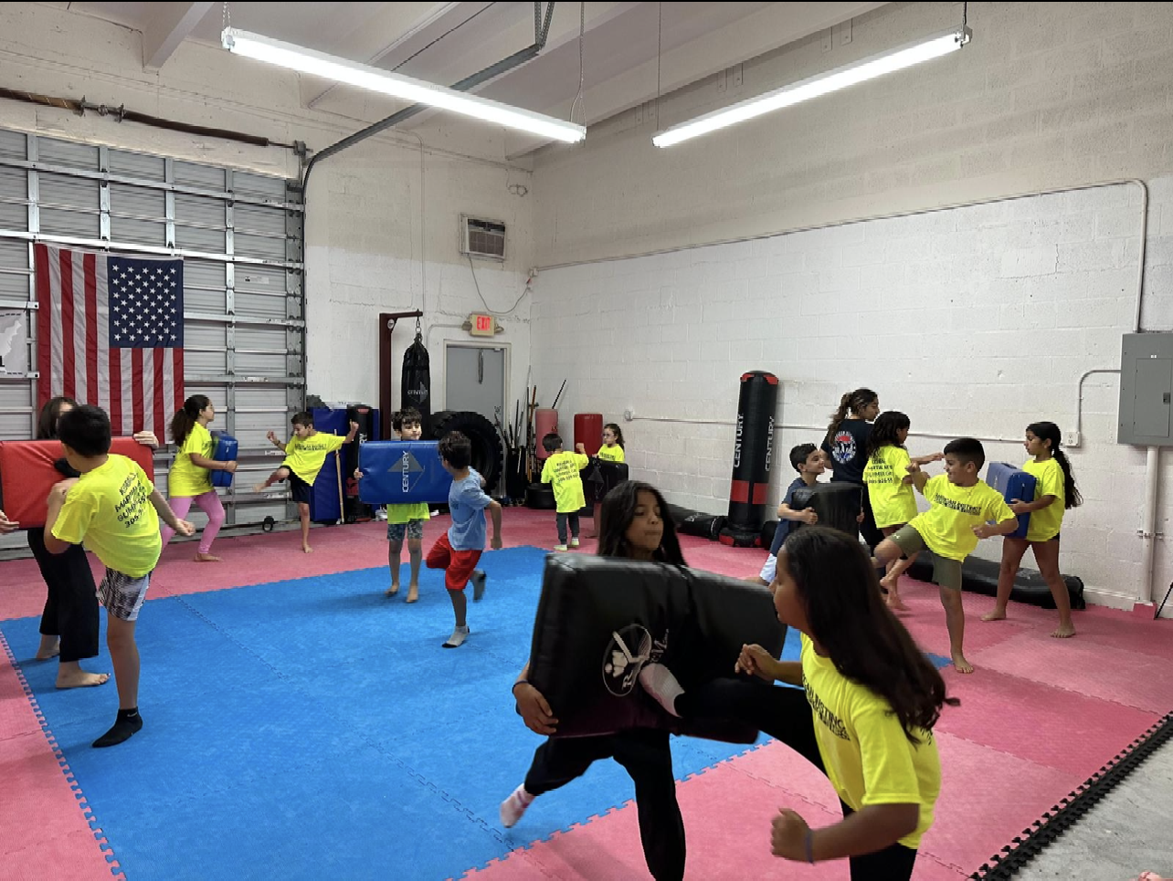 A group of children are practicing martial arts in a gym.