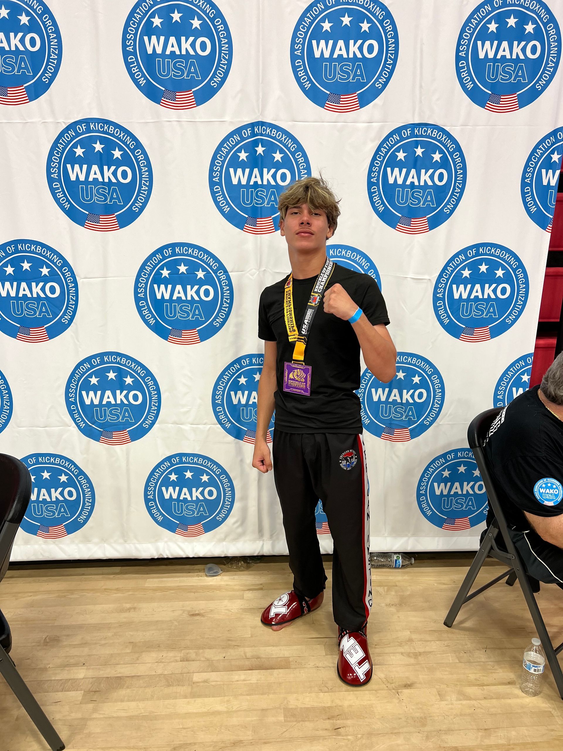 A man is standing in front of a wall that says wako on it.