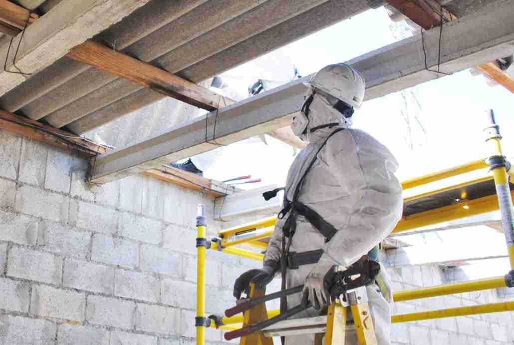 A man in a protective suit is standing on a ladder.