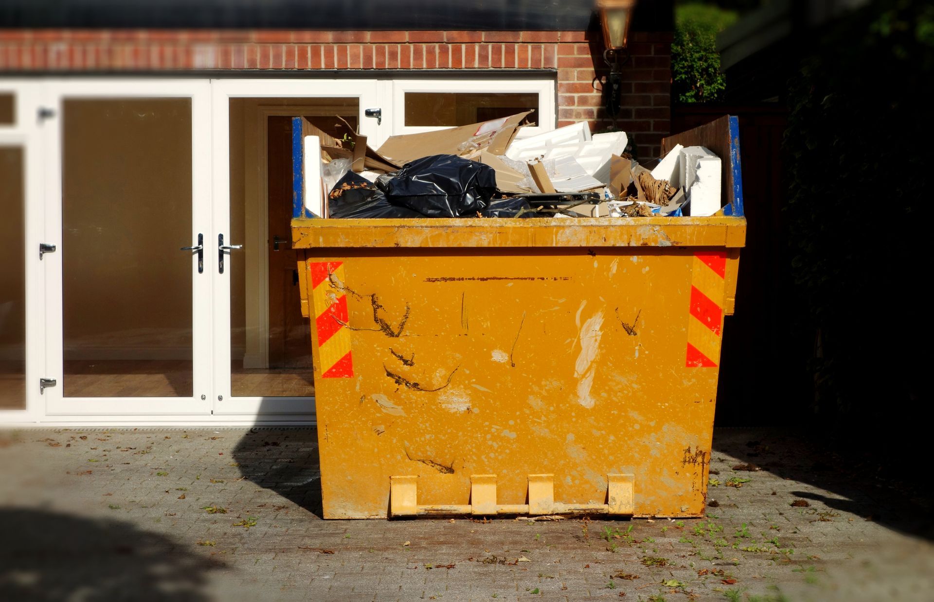 A dumpster rental company’s container placed in front of a home, illustrating waste management.