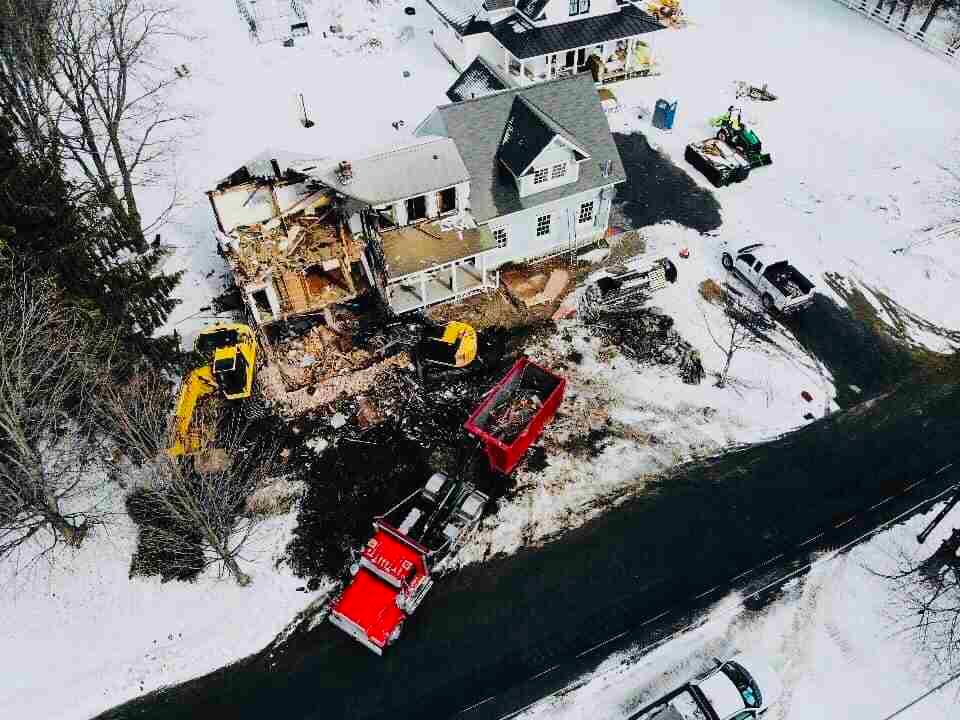 An aerial view of a house being demolished in the snow An aerial view of a house being demolished in the snow
