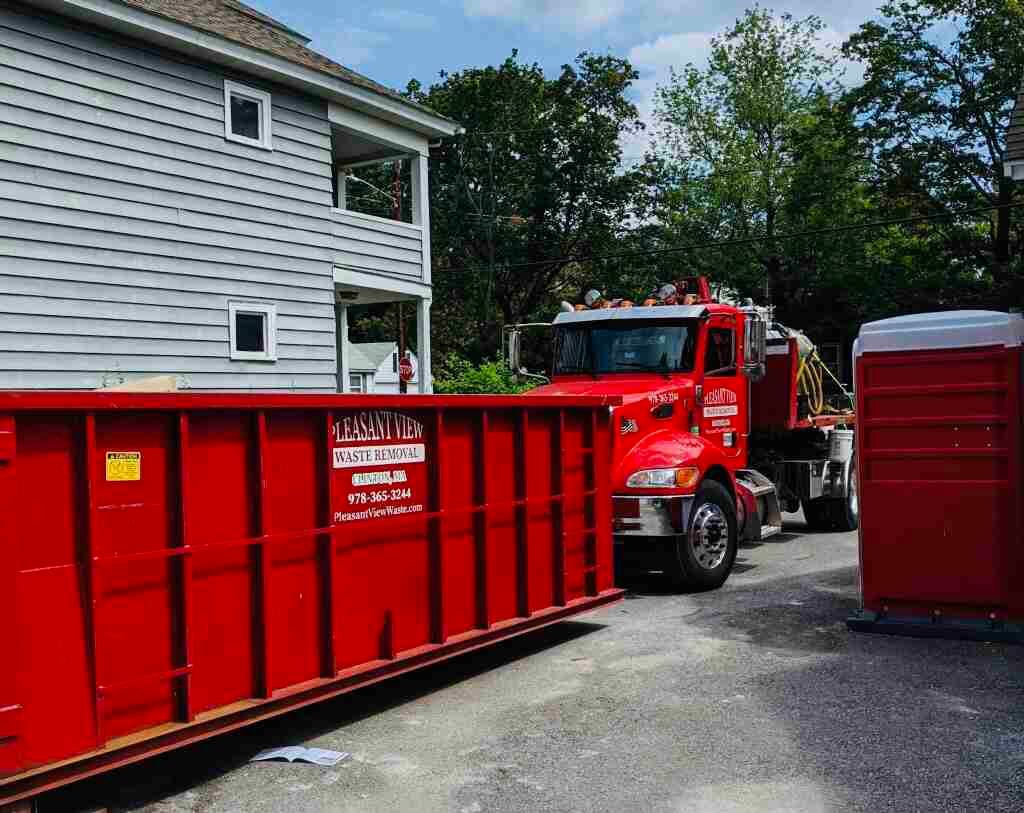 A red dumpster is parked in front of a house.