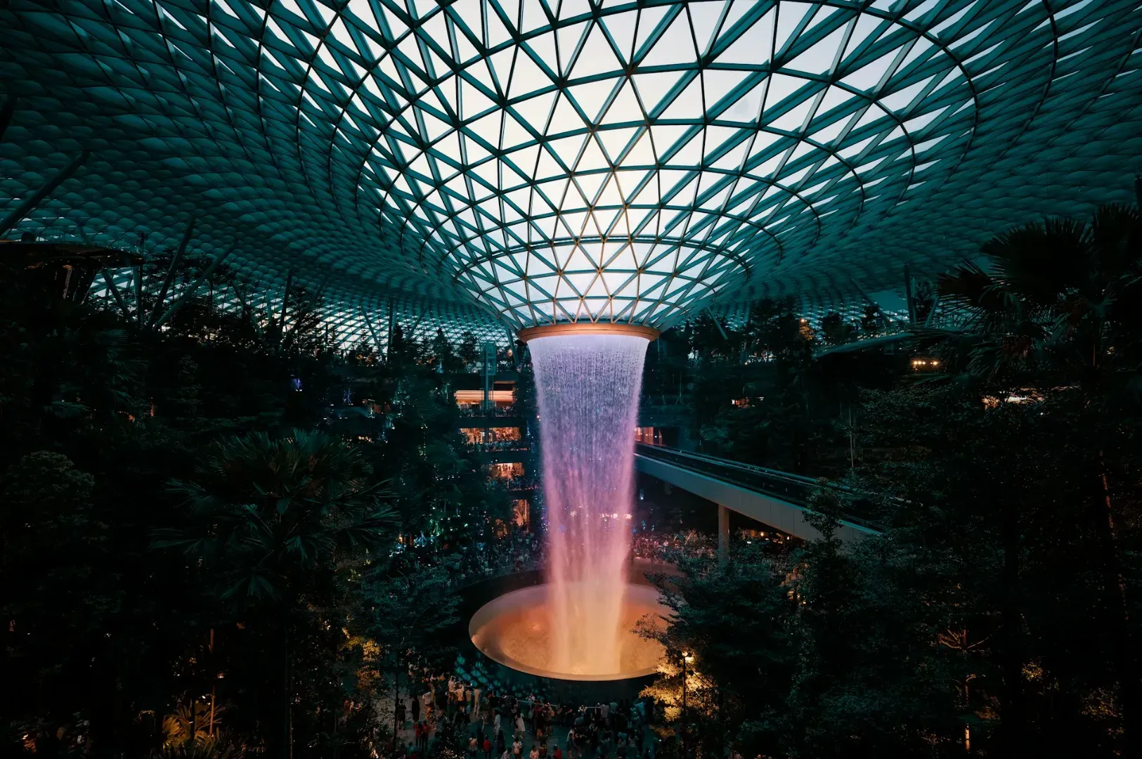 A stunning indoor waterfall cascades from a domed, geometric glass roof.