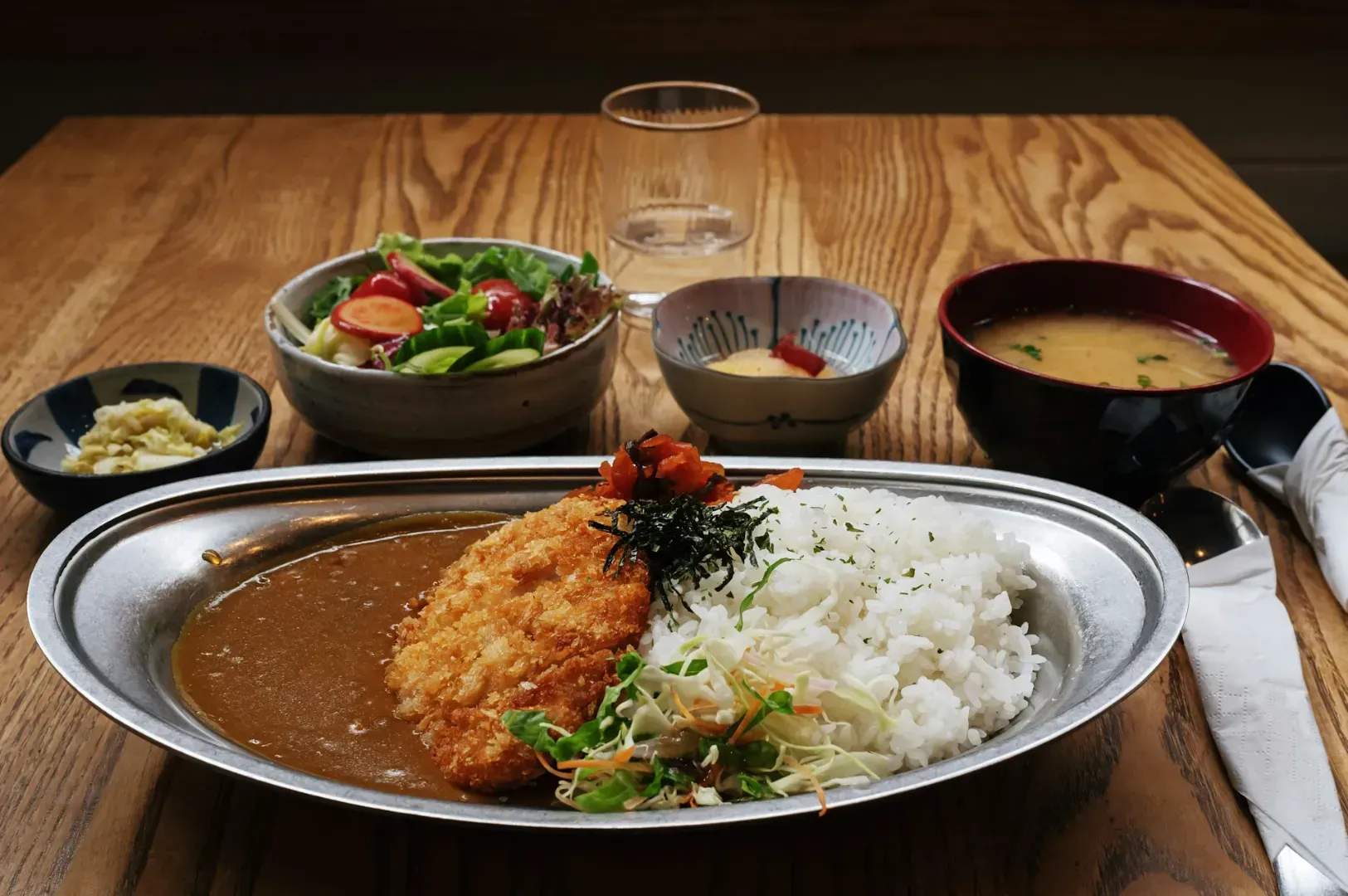 A plated Japanese curry with crispy fried cutlet, rice, and vegetables.