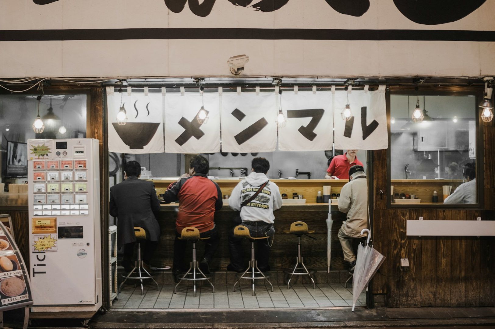 Street view of a cozy Japanese ramen shop at night.