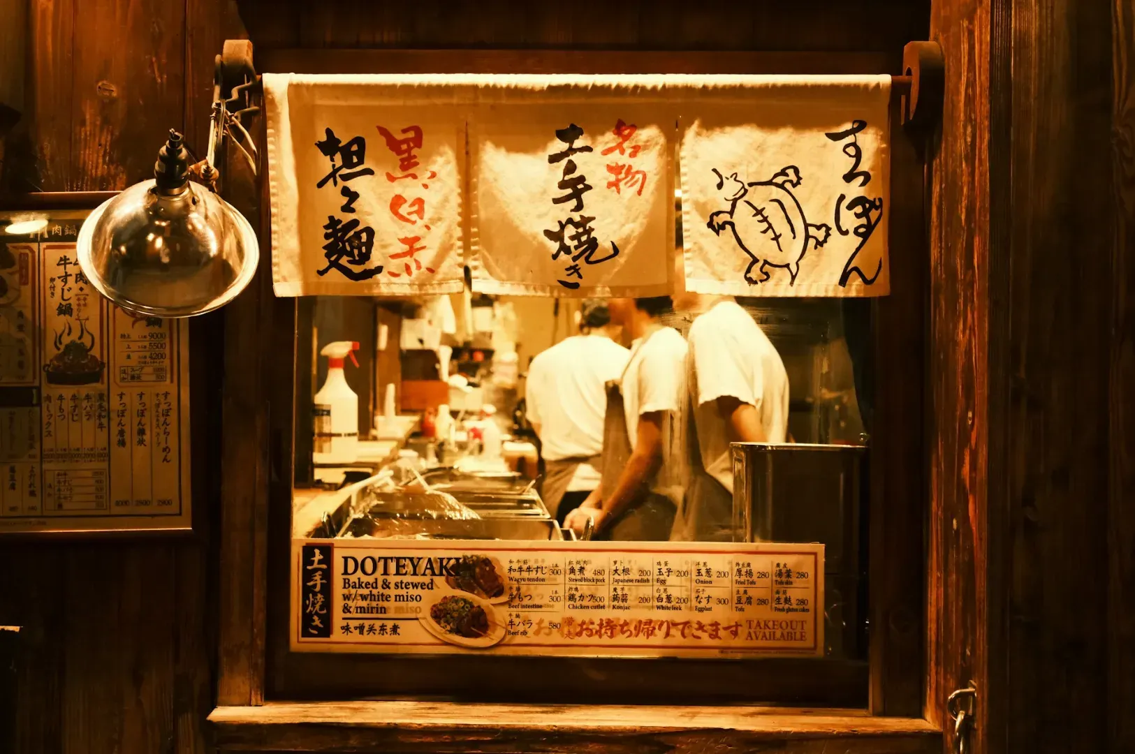 A cozy Japanese restaurant kitchen with chefs in white shirts working.