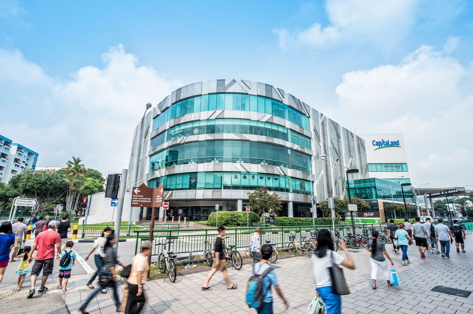 Exterior daytime photo of a curved glass building, identified as a Capitaland mall.