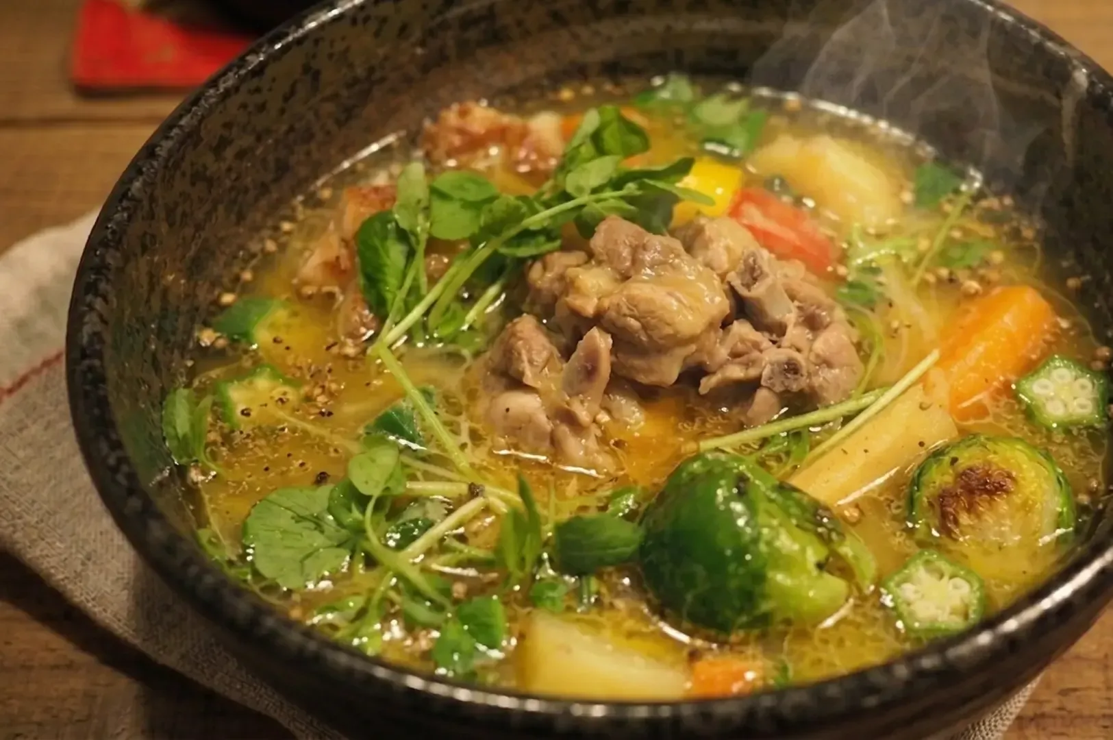 Steaming bowl of soup curry with meat and vegetables