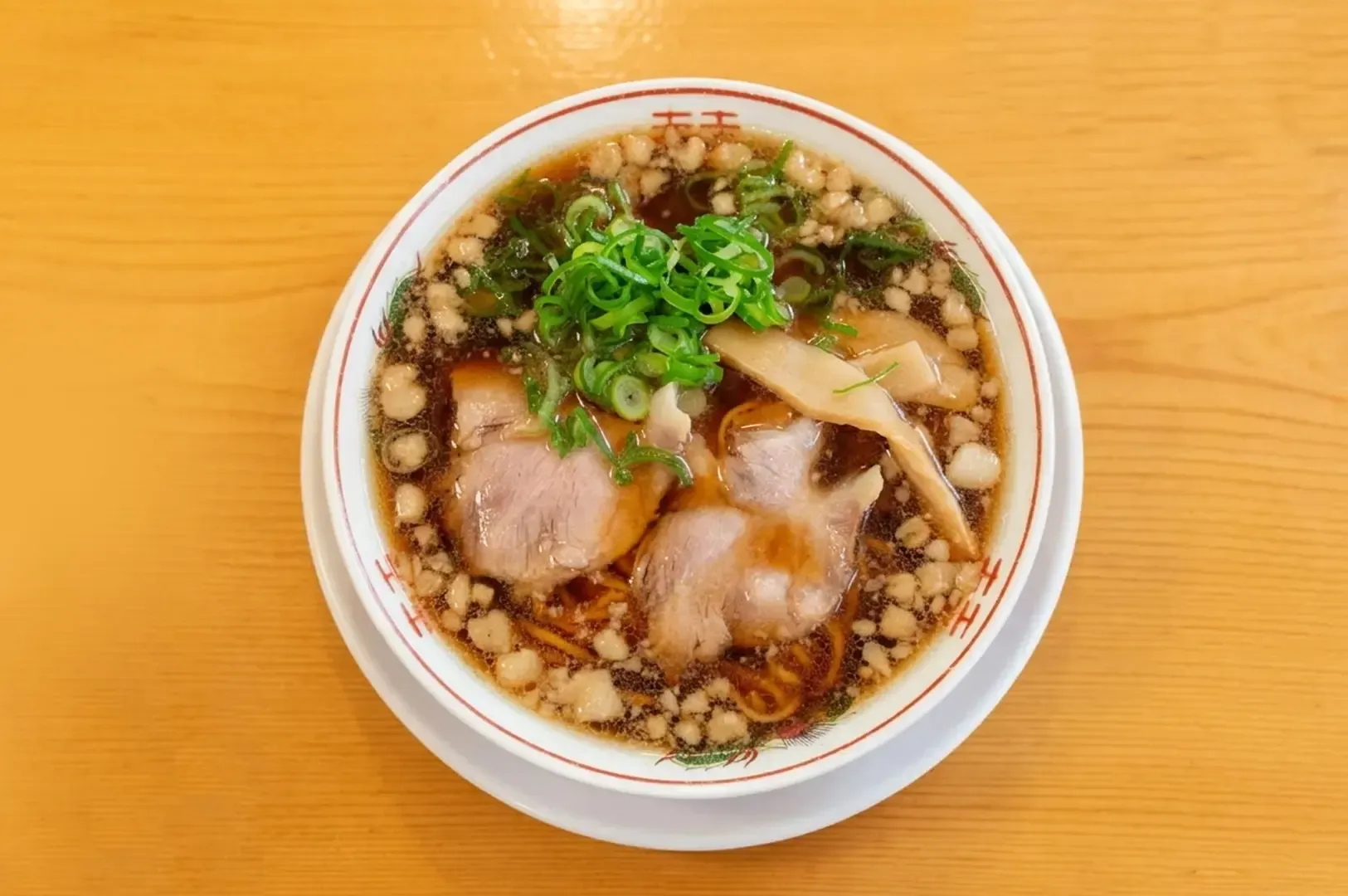 Onomichi ramen bowl with chashu pork, green onions, bamboo shoots, and pork fat in clear soy sauce.