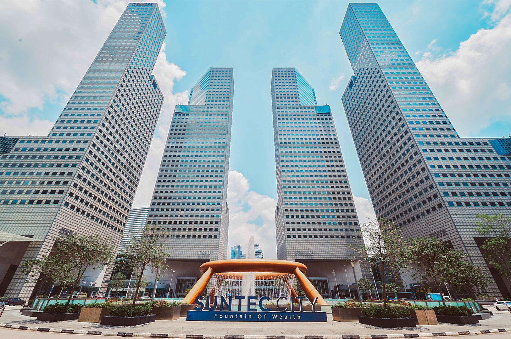 A low-angle shot of Suntec City skyscrapers surrounding the famous bronze-colored Fountain of Wealth