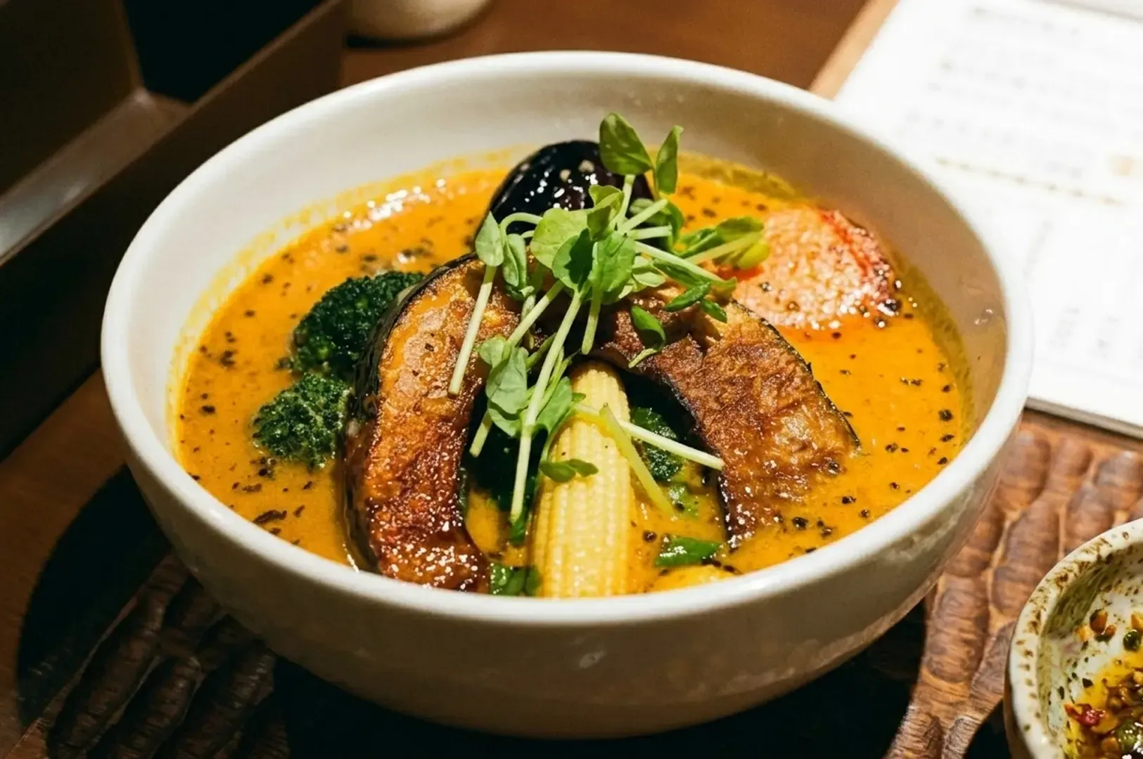 Vibrant bowl of Japanese soup curry filled with roasted pumpkin, zucchini, baby corn, eggplant.