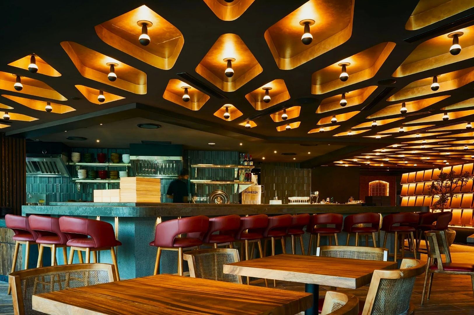 A luxurious bowl of ramen served in a black bowl with red and gold accents, featuring creamy broth, thin noodles, green onions, a central dollop of red seasoning, and neatly arranged slices of pork belly. Set against a wooden table with a bamboo screen backdrop, the scene evokes traditional Japanese dining aesthetics, spotlighting the elegance and depth of flavor found in Singapore’s premium ramen experiences.