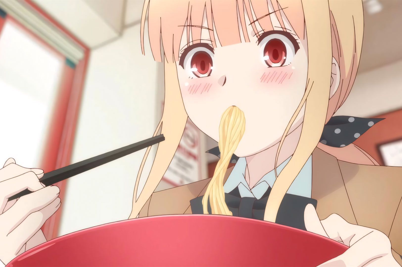 An anime still of a light-haired schoolgirl (Koizumi-san) with rosy cheeks happily slurping ramen noodles from a red bowl with chopsticks, from the series Ms. Koizumi Loves Ramen.