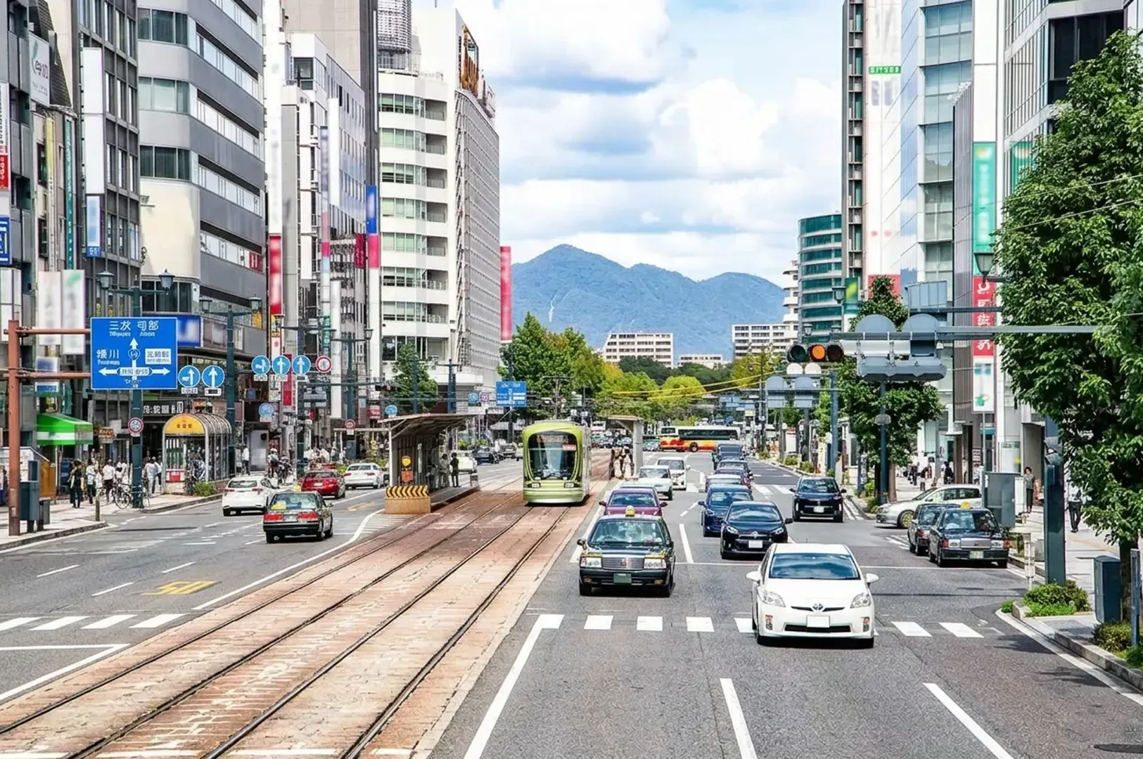 Hiroshima city street with green tram, traffic, modern buildings, and mountains in background.