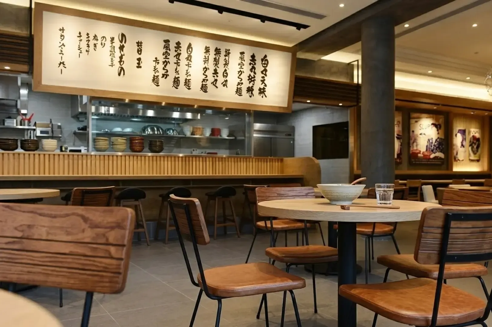 Modern ramen restaurant interior featuring wooden tables and chairs.