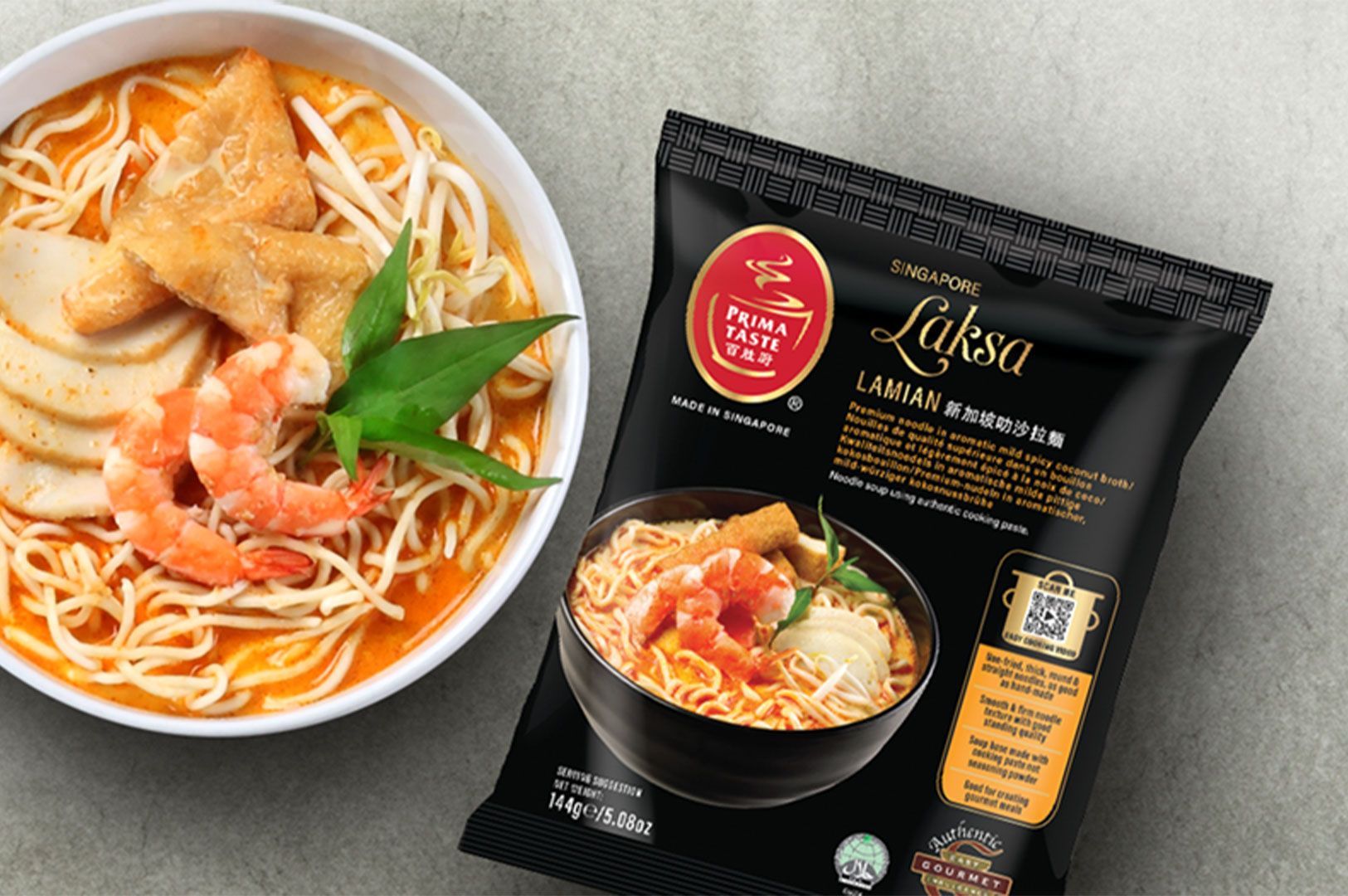 Overhead shot showing a prepared bowl of Singapore Laksa Lamian noodles with shrimp, fish cake slices, and bean sprouts next to a black packet of Prima Taste Laksa instant noodles.
