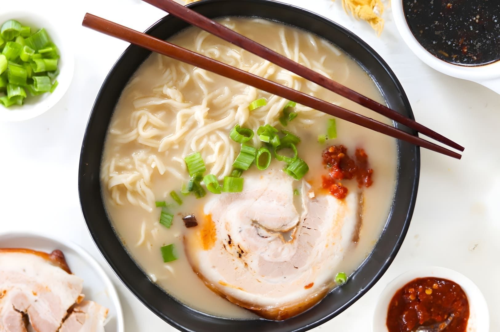 Tonkotsu ramen featuring Chinese noodles topped with tender pork and colorful vegetables in a rich broth.
