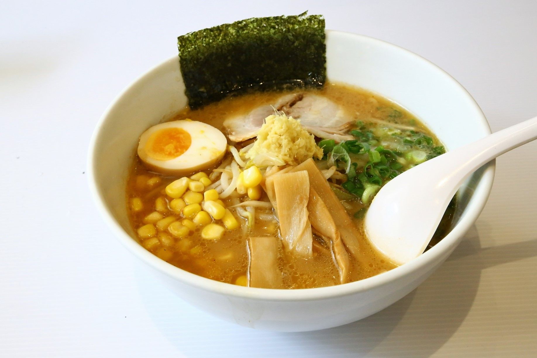 A bowl of Sapporo Ramen Miharu featuring corn, mushrooms, and various other ingredients.