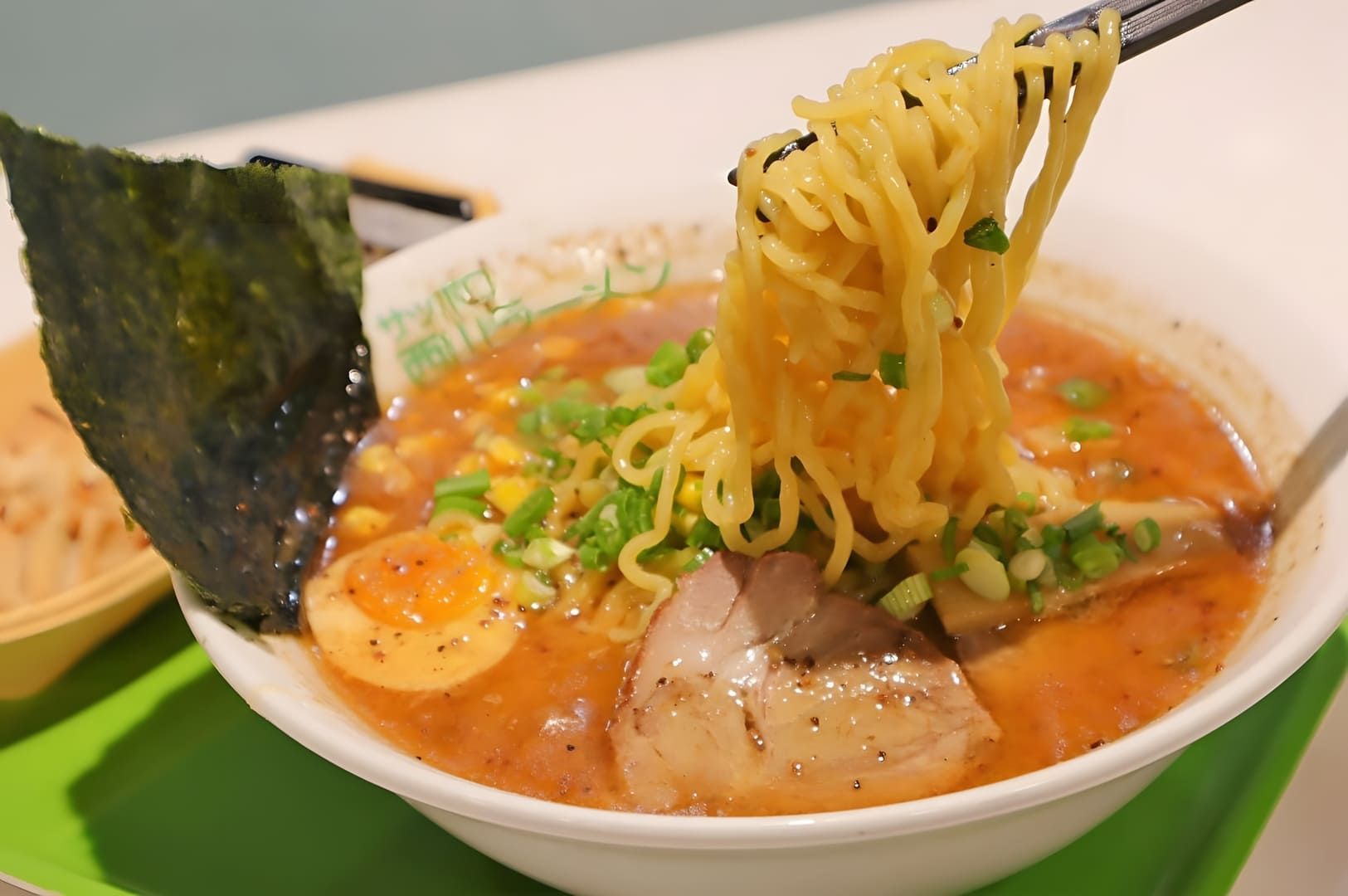 A bowl of Sapporo ramen featuring noodles, tender meat, and garnishes, showcasing a delicious Japanese dish.