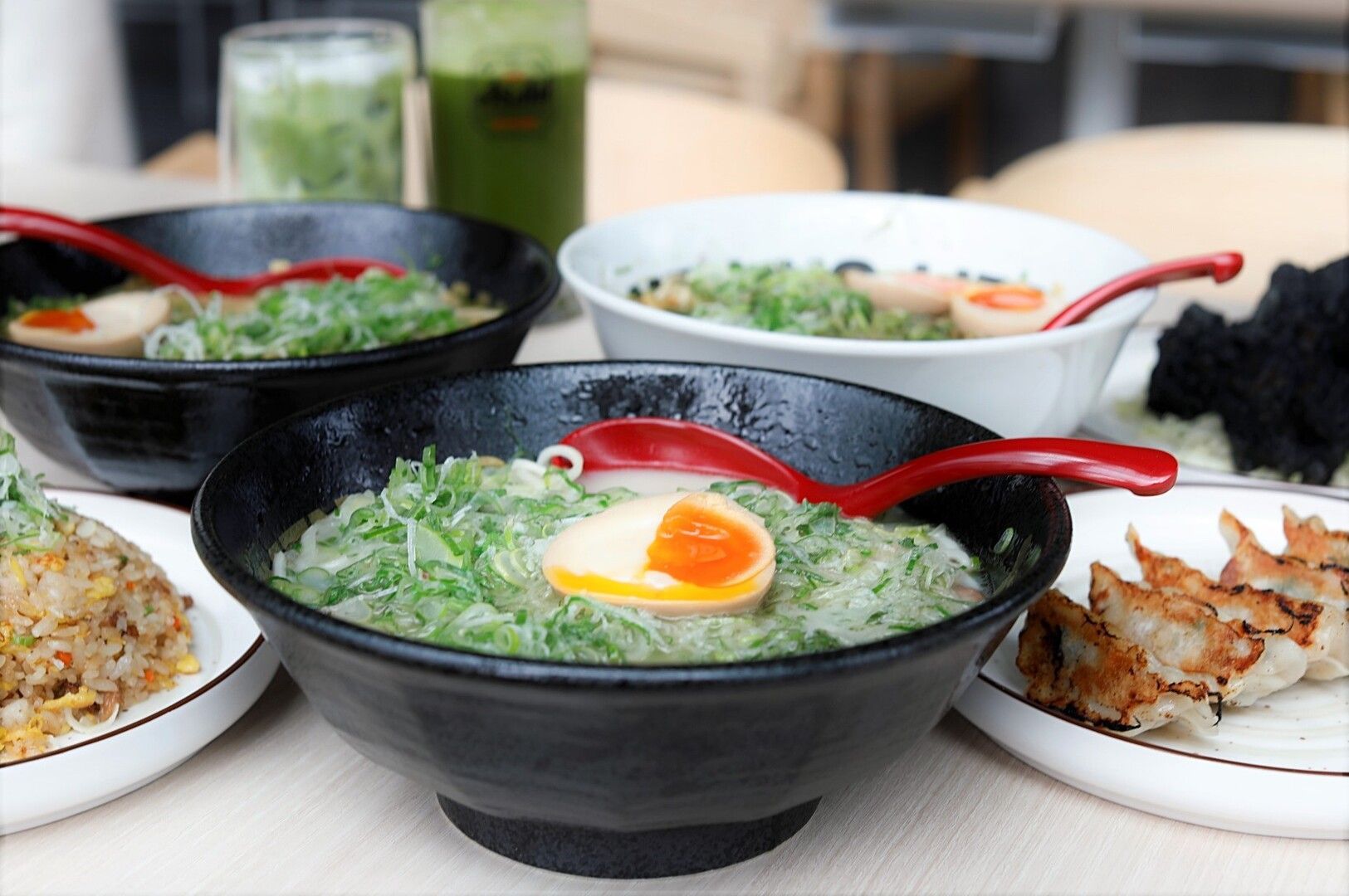 A table set with bowls of Singapore Vegetarian Ramen and various drinks, showcasing a vibrant meal spread.