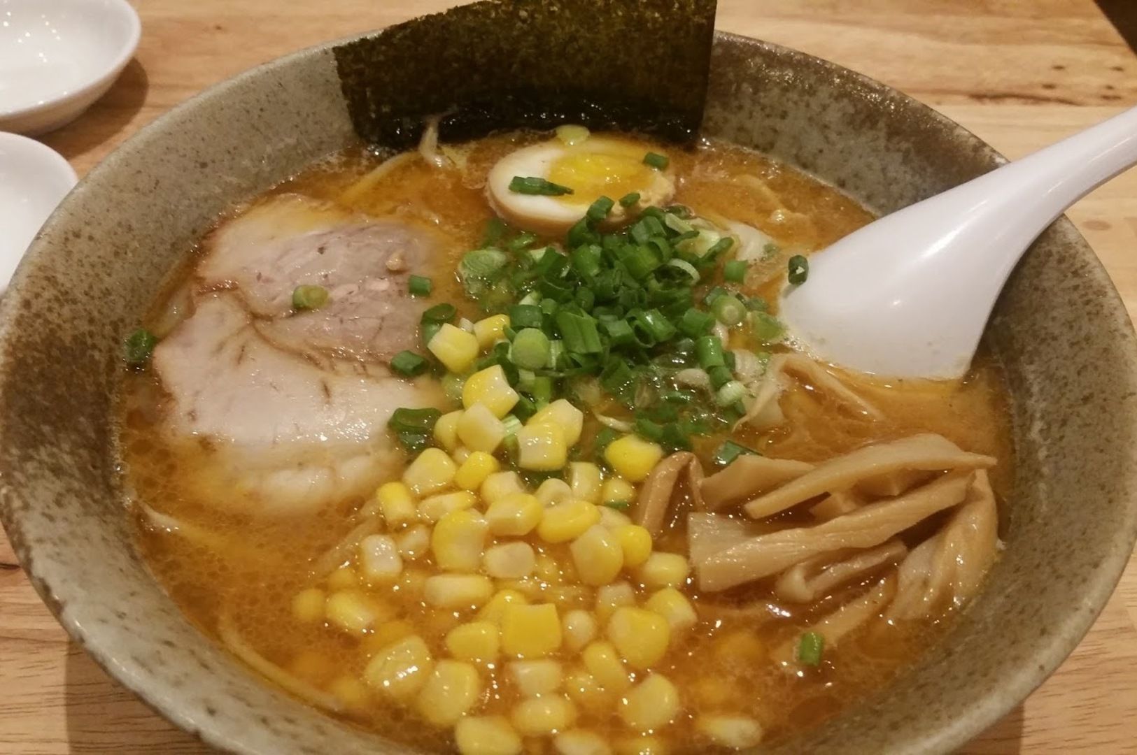 A bowl of Sapporo Ramen Miharu, featuring meat, corn, and assorted vegetables in a rich broth.