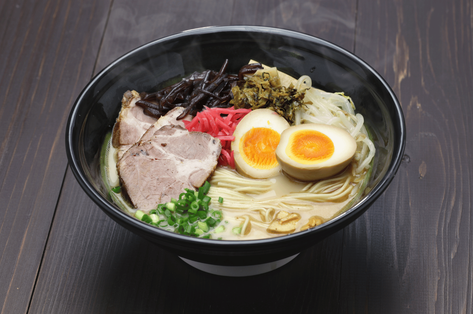A visually balanced bowl of ramen with light broth, pork slices, soft-boiled egg, green onions, pickled ginger, bamboo shoots, bean sprouts, and fermented mustard greens. The fermented toppings lend acidity and vegetal depth, cutting through the richness of the meat and egg while enhancing the broth’s clarity and complexity.
