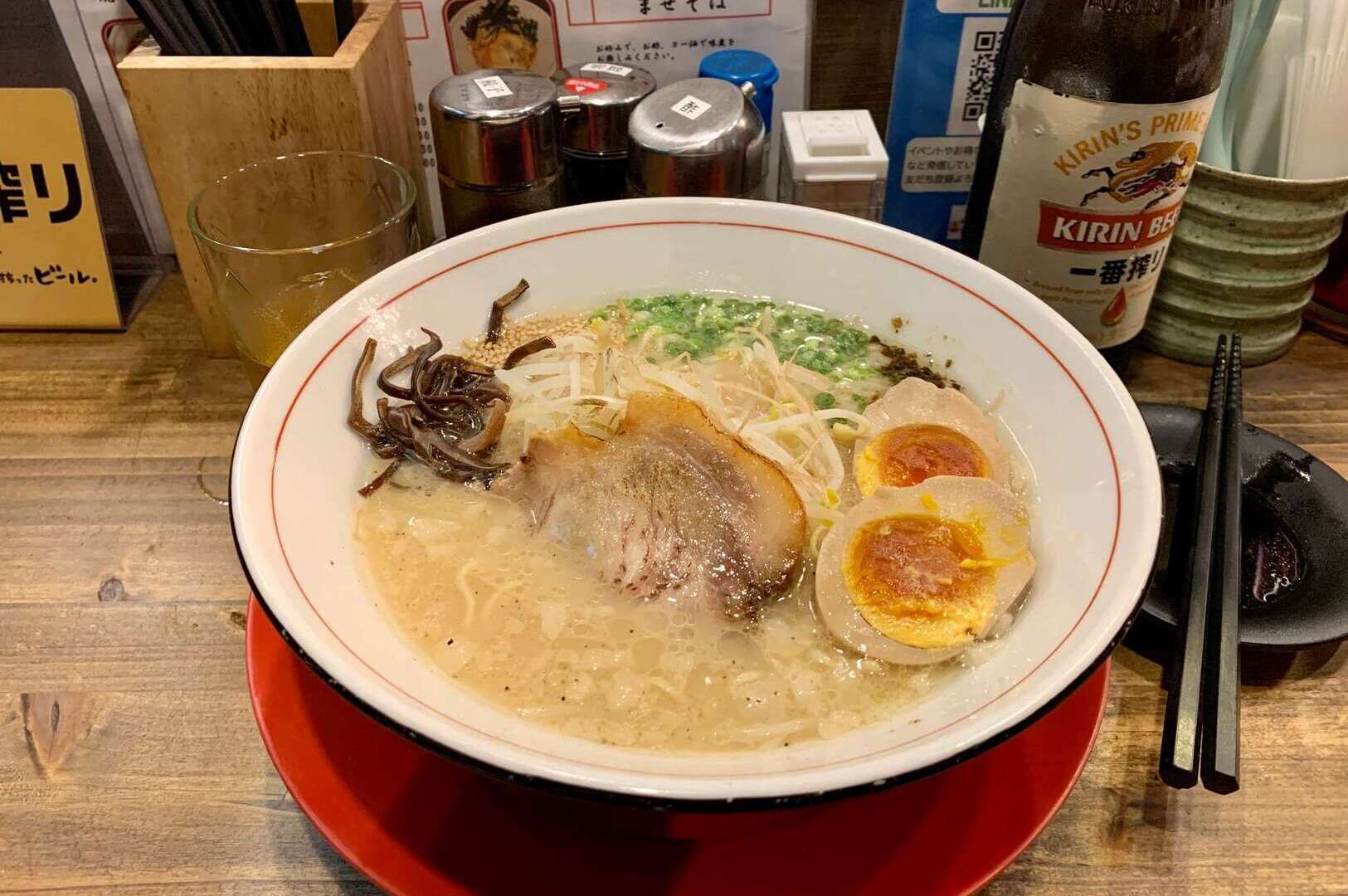 A serving of Hakata ramen featuring meat and eggs, displayed on a rustic table.