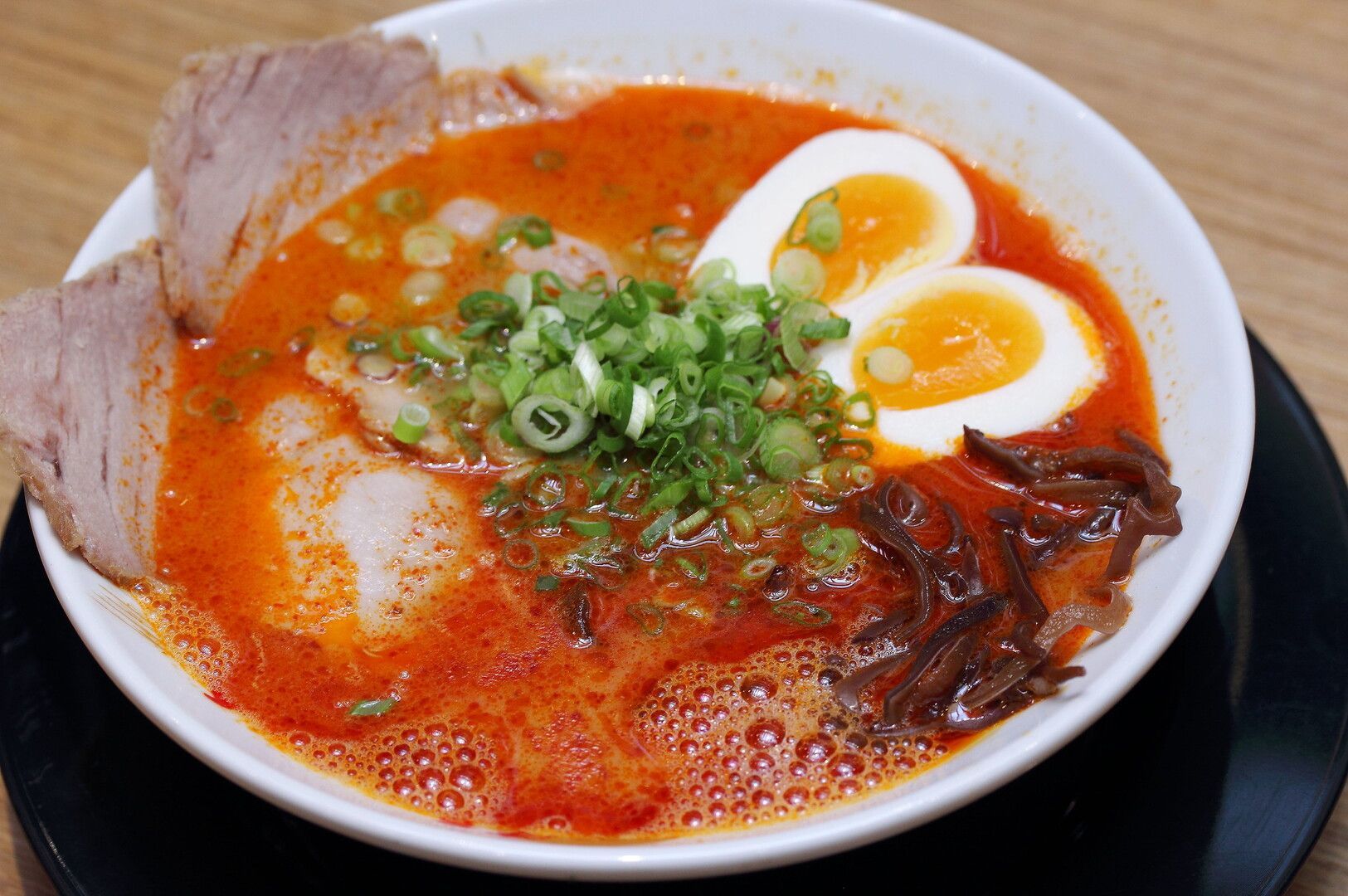 A delicious bowl of Hakata Ikkousha ramen, topped with meat, eggs, and fresh vegetables, located at Chijmes.
