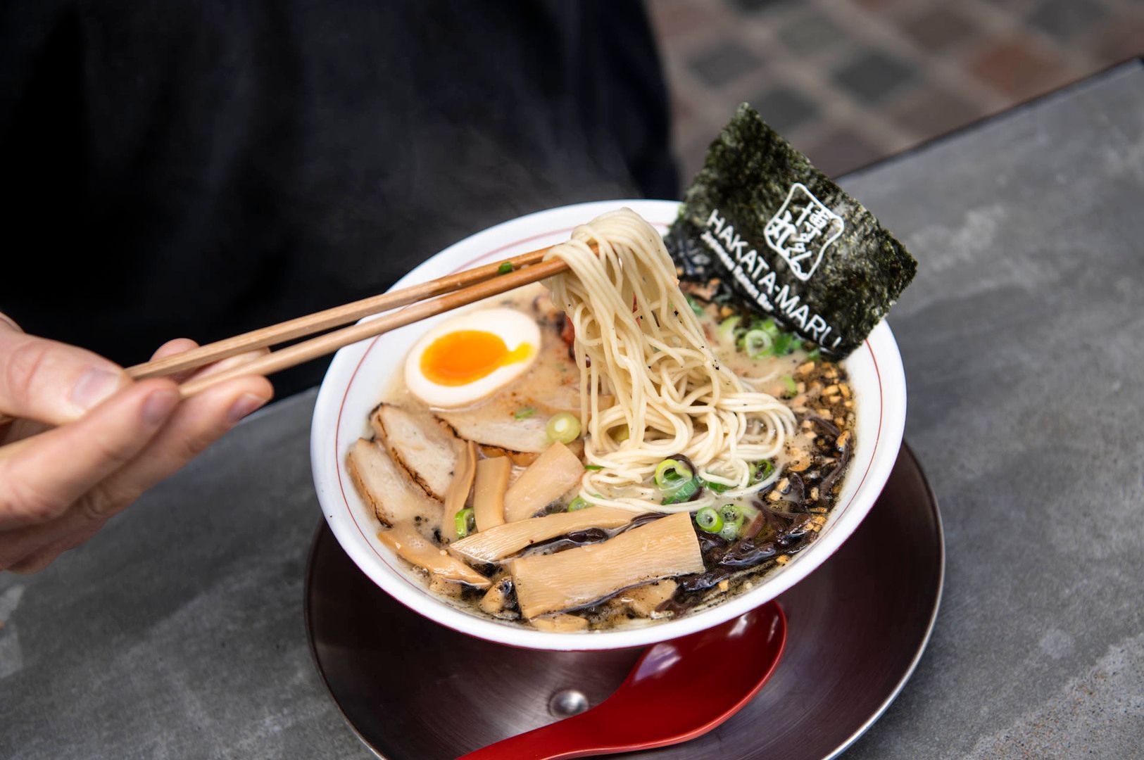 A bowl of Hakata ramen accompanied by chopsticks and a piece of paper, showcasing a delicious meal.